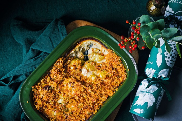 A leek gratin in a green dish with a Christmas cracker in the background