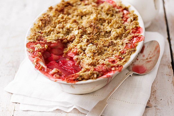 Rhubarb crumble in an oval bowl with a spoon taken out