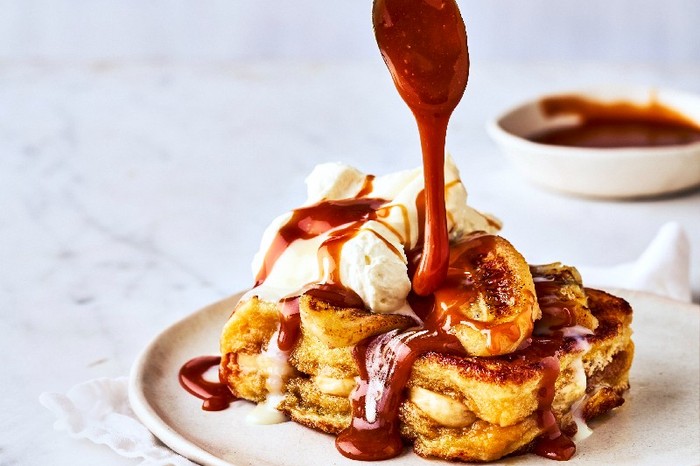 a plate of french toast with melted chocolate being poured from a spoon