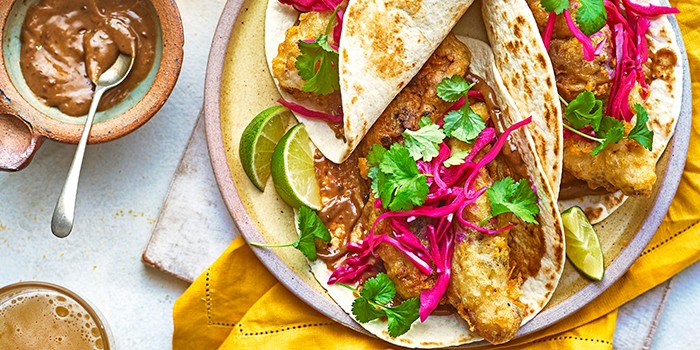 Beer battered fish tacos on a plate with sauce and pickled cabbage