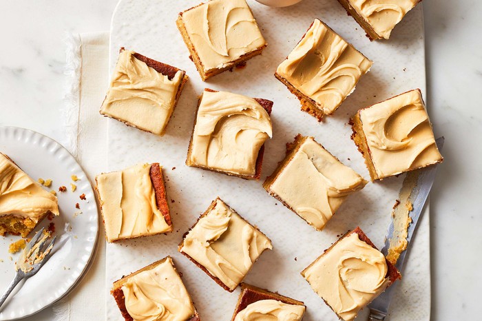 An iced sheet cake cut into squares with coffee on the side