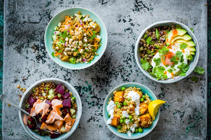 Four bowls of grains on a dark background