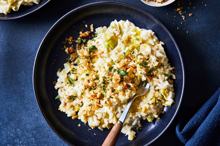 Leek risotto in a bowl topped with fried anchovy and breadcrumbs