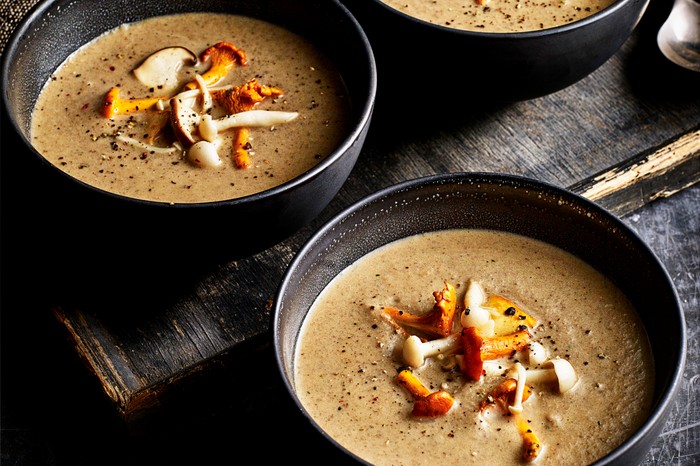 Three bowls of mushroom soup, topped with pickled onions