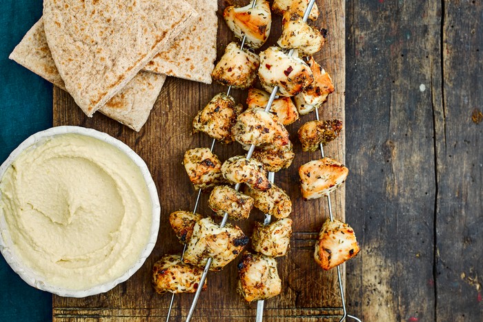 Greek Chicken Skewers on a Board with Hummus and Flatbreads