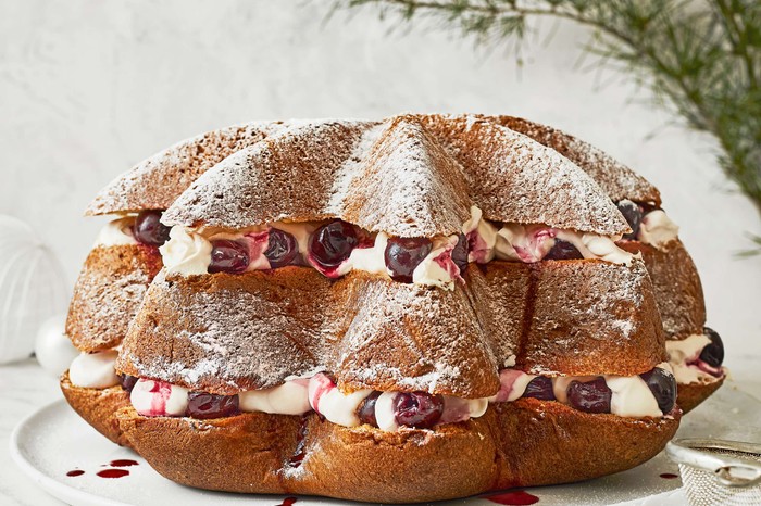 A triple-layered cake filled with cream and fresh fruit on a serving plate