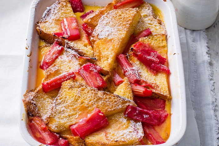 Vibrant Rhubarb and Custard Bread and Butter Pudding served in a rectangle white dish on a grey wooden table