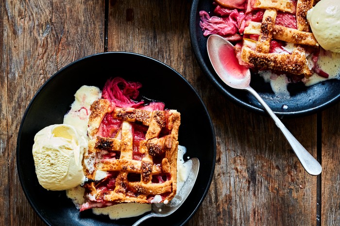 Two black bowls filled with a slab of rhubarb pie and a side of vanilla ice cream