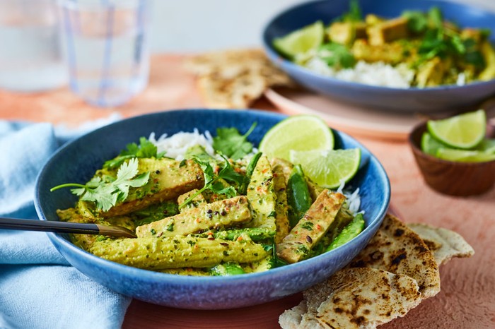 Bowl of tempeh curry in focus at forefront of image with another out of focus in the background