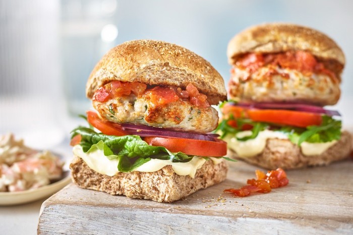 Two Turkey Burgers in Buns with Lettuce and Tomato on a Wooden Board