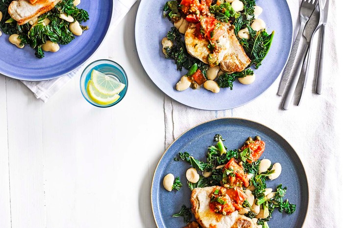 Tuscan pork loin steaks with butterbeans and greens on plates