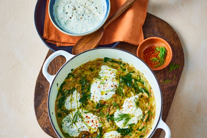 Pot of orzo topped with yogurt and dill next to a bowl of yogurt