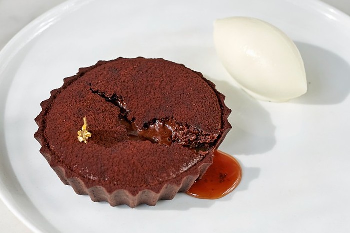 A chocolate tart on a white plate with a marble background