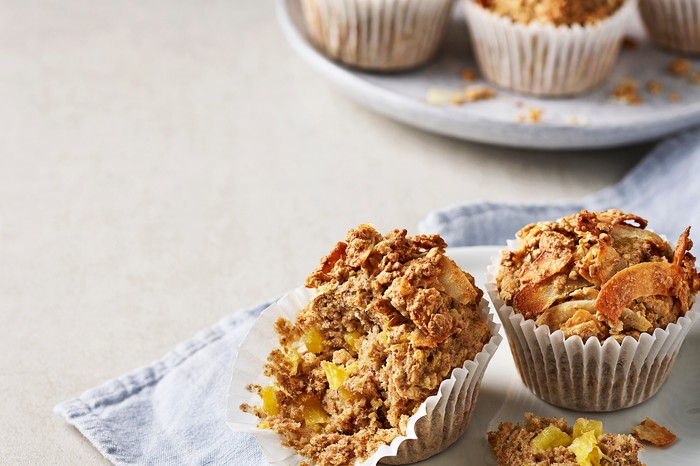 Three golden muffins in paper cases on a pale blue napkin